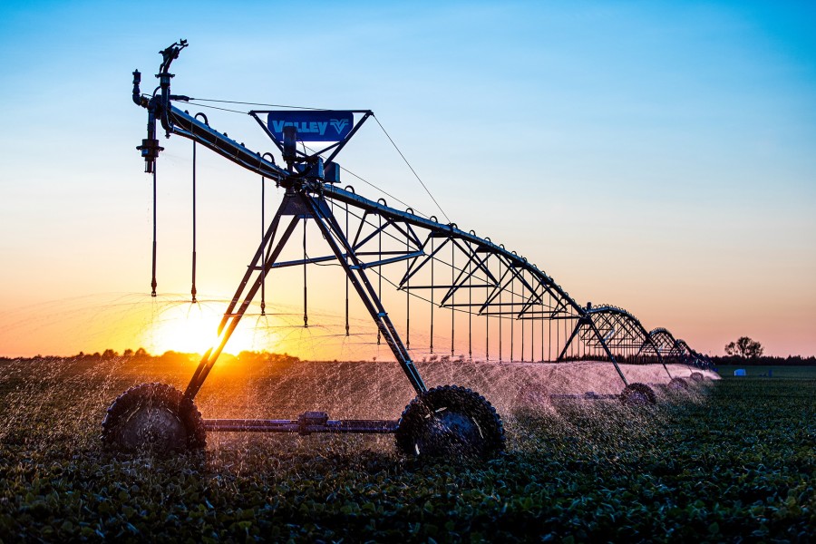 Valley center-pivot irrigation system watering a field at sunset